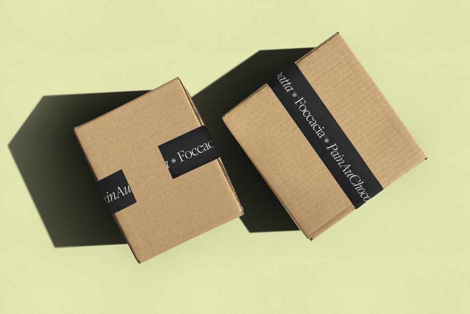 Two cardboard boxes with black tape strips on pale yellow backdrop