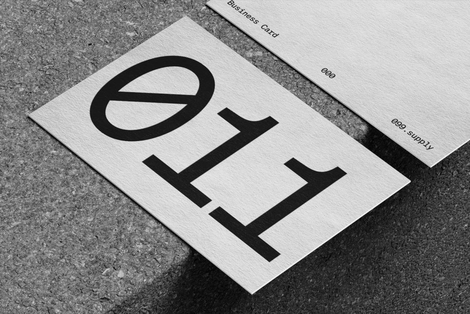 White business card with black logo beside matching envelope on rough surface