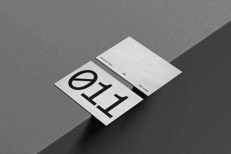 White business card with large black logo next to envelope on gray backdrop
