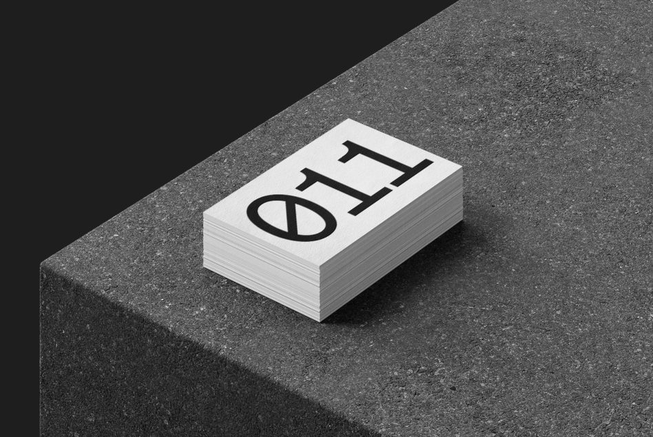 Small white business card stack with black logo on gray textured surface