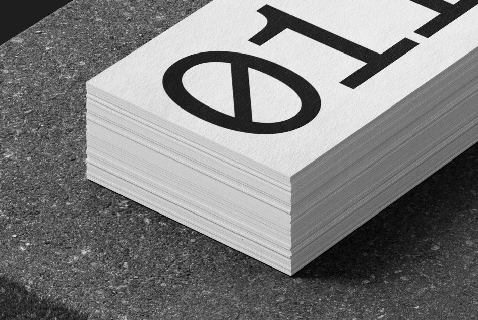 Thick stack of white business cards with bold black logo on concrete ground