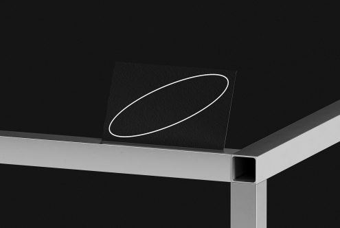 Elegant black paper mockup with white elliptical design on modern metal shelf, showcasing minimalistic presentation style for graphics and branding.