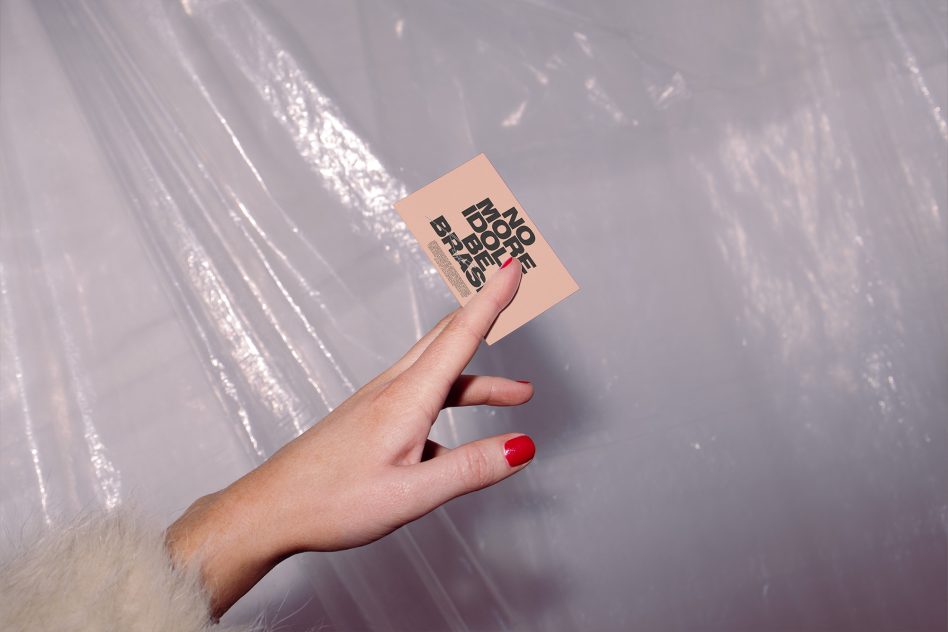 Kraft business card with stacked typography held in hand near white tulle fabric