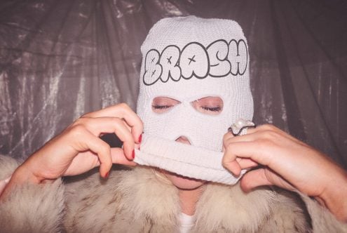 Person in white balaclava with bubble letter outline design on forehead face covering