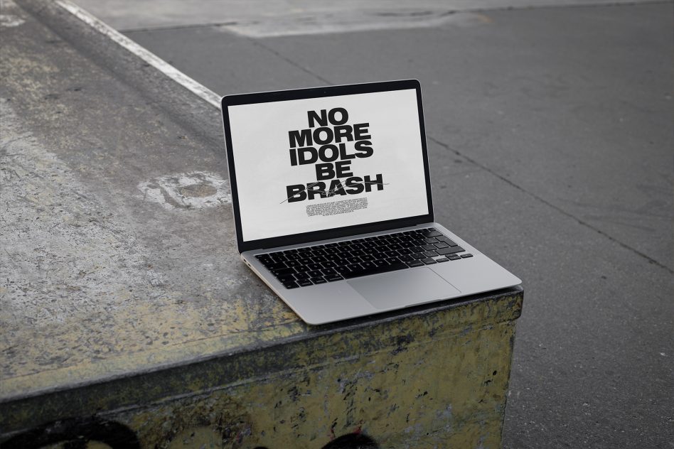 MacBook on rusty yellow metal surface displaying white background with dark typography