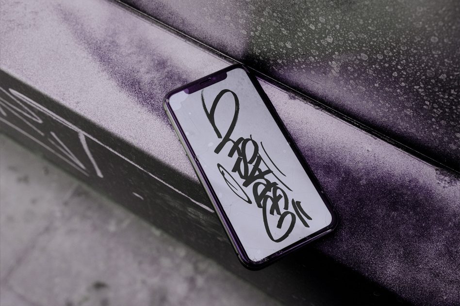 Smartphone on wet purple surface displaying hand-drawn lettering design