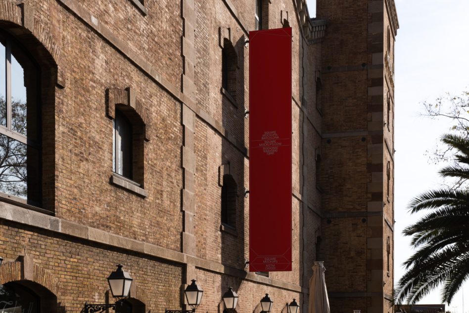 Deep red vertical banner mockup mounted on historic brick building wall