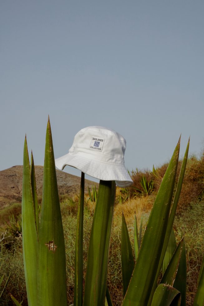 White bucket hat on agave plant in natural setting, clear sky, ideal for mockup presentations, apparel design showcase, trendy headwear.