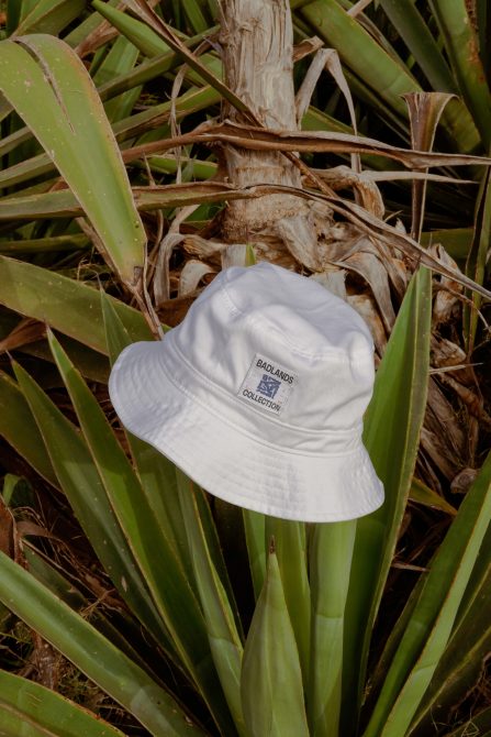 White bucket hat with logo mockup on tropical plant, design asset for fashion accessories, natural setting, realistic texture.