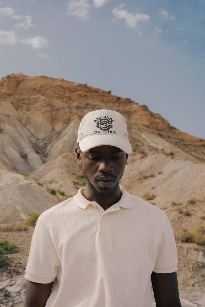 Young man in cap and polo against rocky landscape perfect for fashion mockups, apparel design display, outdoor lifestyle graphics.