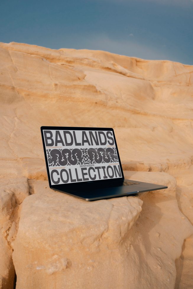 Laptop with graphic design screen display on sandy rock formation for designers, showcasing Badlands Collection, ideal for mockup and template design.