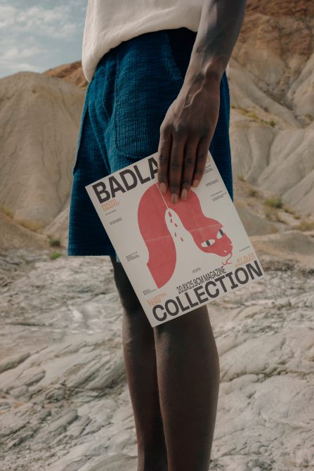 Person holding cream Badlands Collection poster with red design