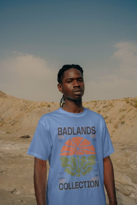 Guy in light blue Badlands tee standing in desert landscape looking straight ahead