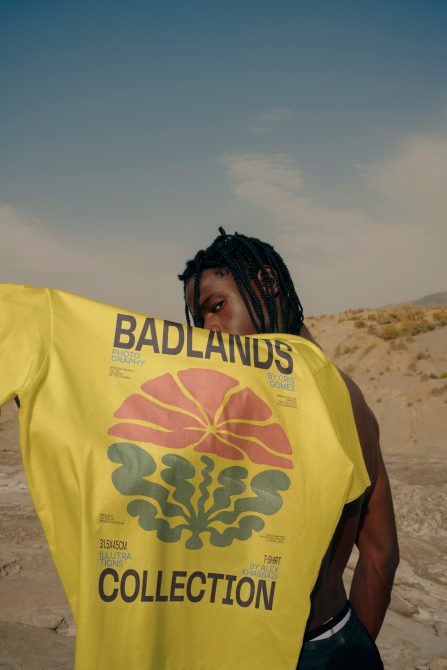 Mockup of a person holding a yellow t-shirt with graphic design in natural outdoor setting, showcasing clothing mockups for fashion designers.