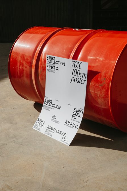 Promotional poster mockup for the K1NK1 Collection leaning against red industrial drums on concrete floor, showcasing modern graphic design.