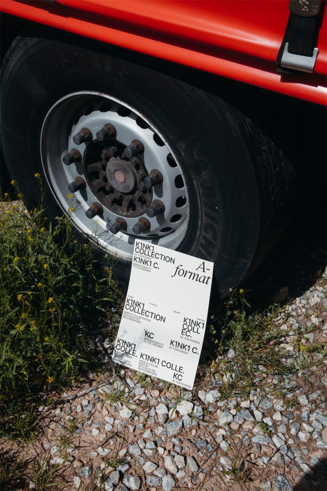 Red truck wheel close-up with graphic font design template card on ground, perfect for mockups and typography projects for designers.