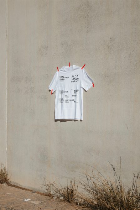 White T-shirt mockup pinned to textured concrete wall with shadows, realistic apparel presentation for print design.