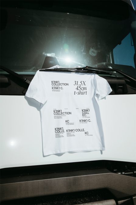 White t-shirt mockup with black text design, draped over car dashboard, clear daylight, ideal for graphic presentations and apparel designs.