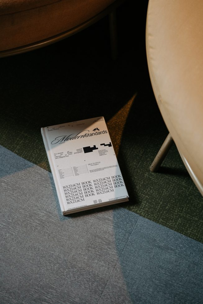 Vintage style magazine mockup on a carpeted floor next to a tan chair, showing a design template perfect for showcasing layouts and graphics.