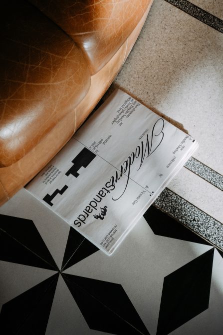 Retro newspaper mockup on terrazzo floor with leather couch, showcasing elegant typography and classic design, appealing to professional designers.