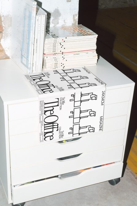 Stacked magazines on white cabinet drawer with Modern Standards publication visible on top