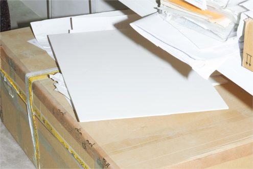 Blank white paper mockup on a workspace with scattered documents and packaging, ideal for presentation template designs.