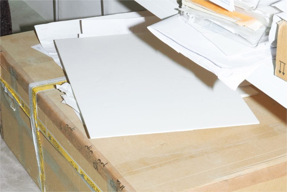 Blank poster mockup on wooden desk with cardboard box