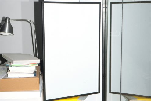 Blank poster mockup in a frame with desk lamp and books, ideal for graphic design presentations and portfolio templates.