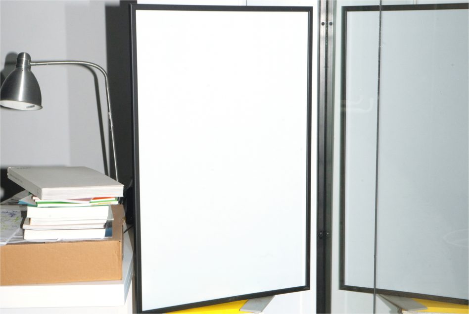 Large framed poster leaning against wall next to desk with lamp