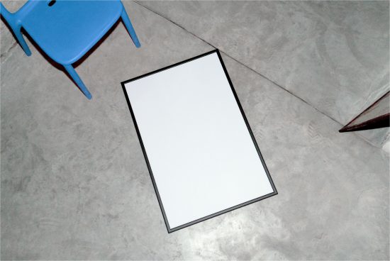 Blank vertical poster mockup on a concrete floor with blue chair, ideal for graphic design portfolio presentations.