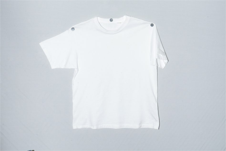 Oversized white tee laid flat on gray background with metal shoulder details