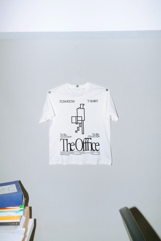 White t-shirt with graphic design mockup, office theme, displayed on a wall, modern presentation for t-shirt designers and apparel shops.