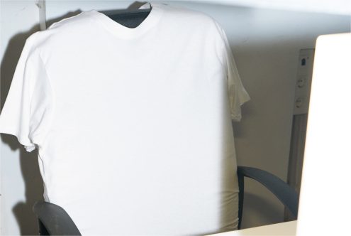 Blank white t-shirt mockup on hanger for apparel design display, suitable for graphic overlays and presentation by designers.