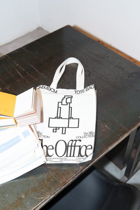 Contemporary tote bag mockup laying on a vintage desk beside color swatches, ideal for showcasing designs for accessories, stationery.