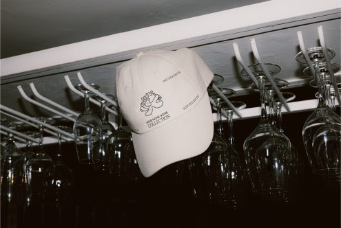 Beige baseball cap mockup with logo hanging on a rack above wine glasses, suitable for design branding presentations.