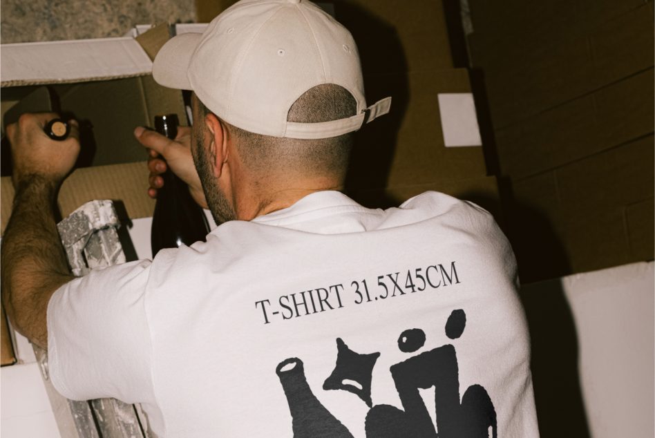 Man in white hat and t-shirt with back print working on packing, design mockup inspiration for t-shirt graphics and branding.