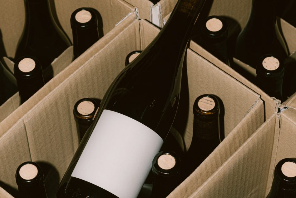 Wine bottles in cardboard box with blank label mockup in center