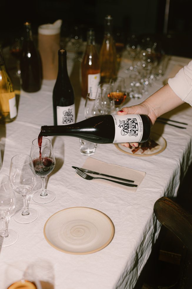 Elegant wine bottle pouring in glass, set on a table with dishes, designers can utilize for realistic dining scene mockups.