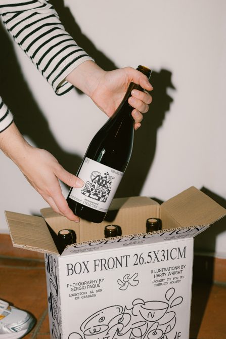 Person unpacking bottle with custom label from box, perfect for mockup, packaging design, branding showcase, and product presentation.