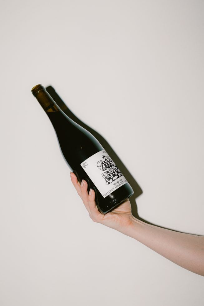 Hand holding wine bottle with a custom label mockup on a plain background, ideal for label design presentation, packaging mockup, graphic display.