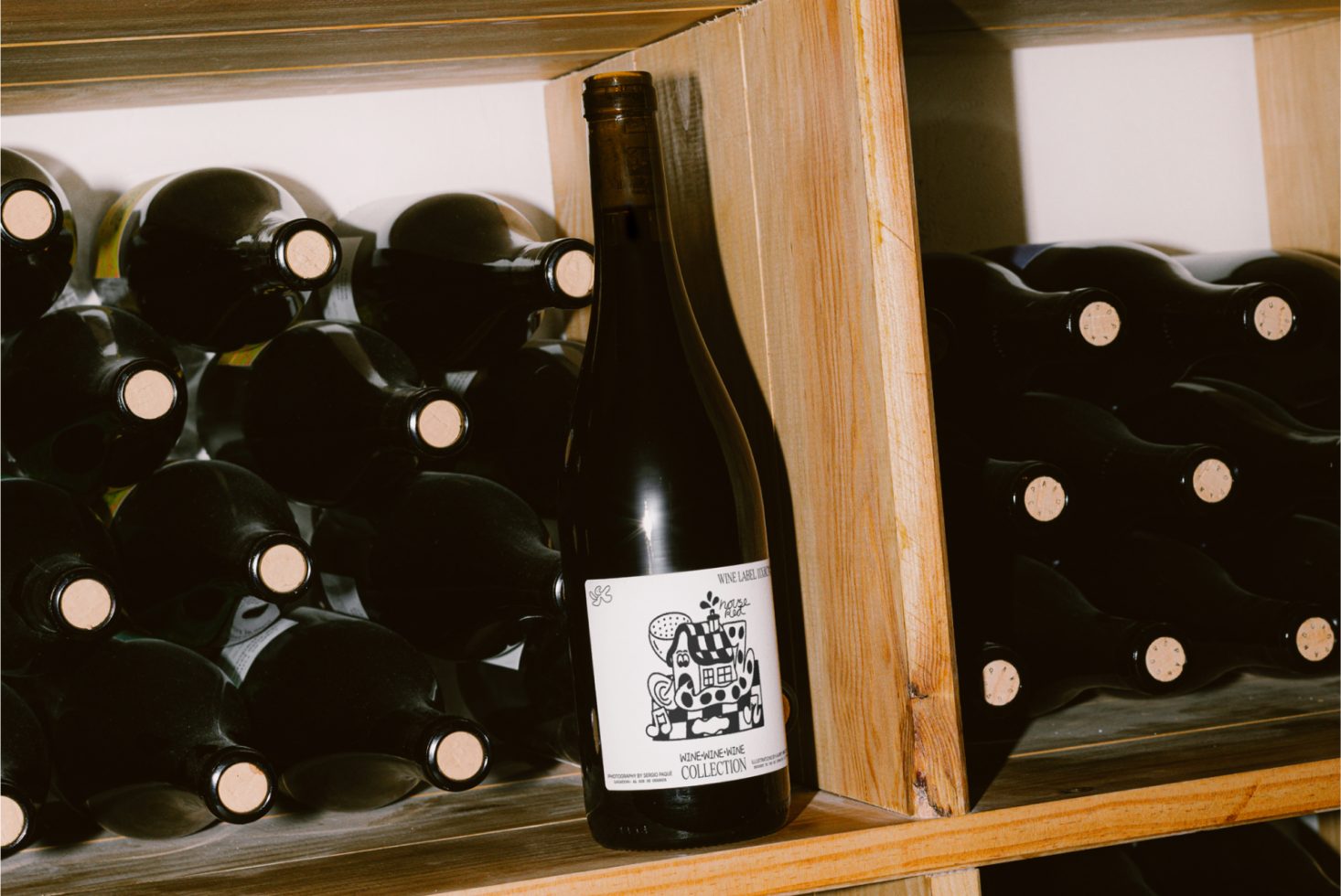 Wine bottle on wooden rack with unique label design, amidst collection of dark bottles, ideal for Mockup and Graphics category.