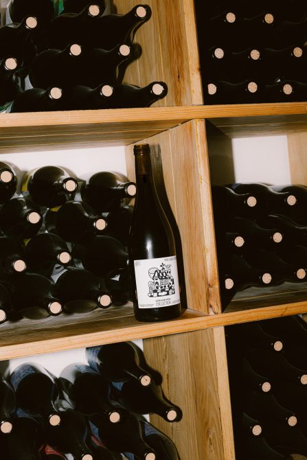 Wooden wine rack with bottles and a single bottle with label in focus, ideal for mockup, product design, and graphic display.