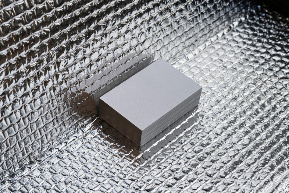 Stack of blank business cards on textured silver foil background mockup for graphic designers.