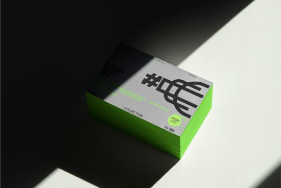 Stack of business cards with modern design in sunlight and shadow, showcasing bold typography and bright edge printing for mockups or templates.