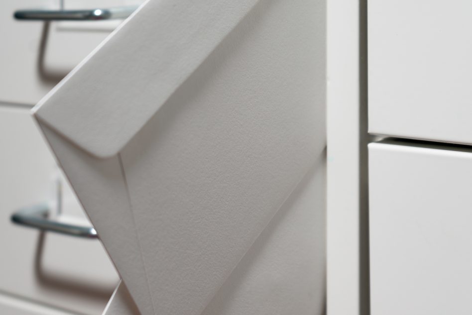 White envelope mockup leaning against wall with window light