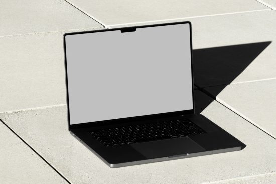 Laptop mockup with blank screen on concrete surface in sunlight, ideal for website design presentations and digital templates.