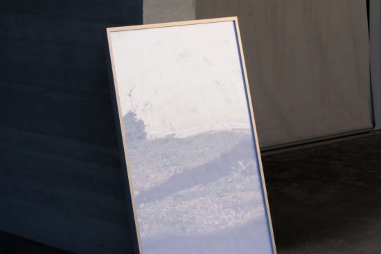 Blank poster mockup with urban reflections, standing against a grey wall, suitable for presentation of designs and graphics.