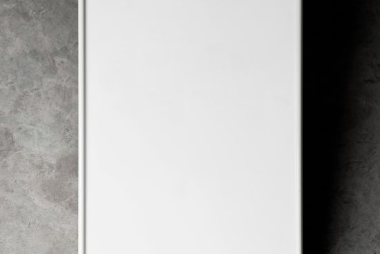 Vertical poster mockup with blank white space for design display, set against a textured gray wall. Perfect for graphics and templates presentation.