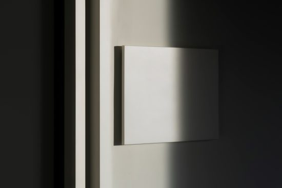Minimalist mockup of a blank wall-mounted frame with elegant shadows, ideal for showcasing designs or artwork.