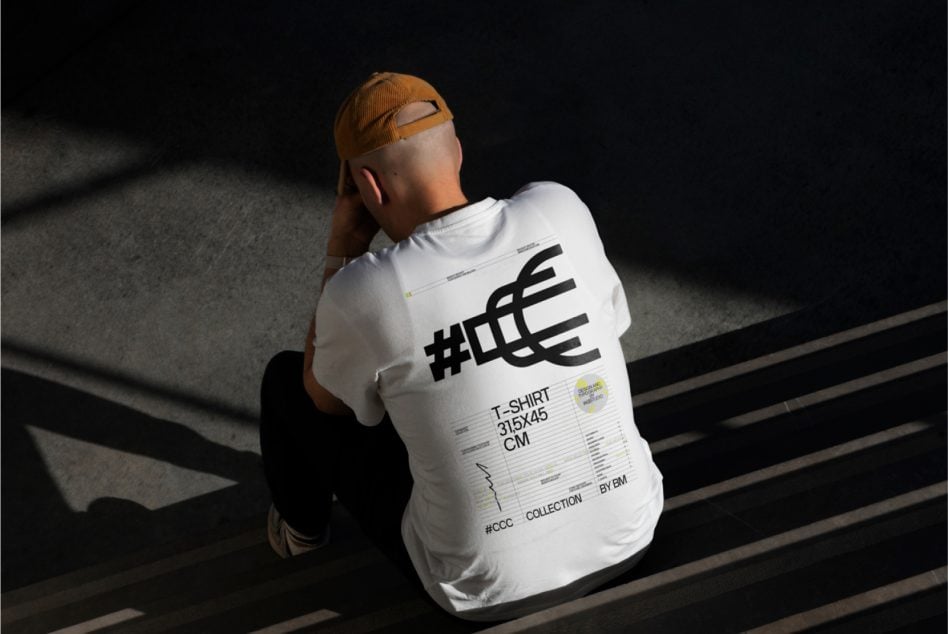 Person in white tee showing back print with black logo design on dark background